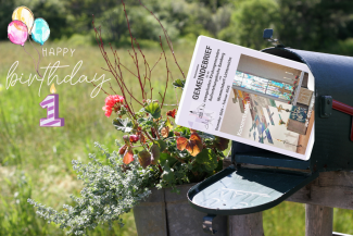 Gemeindebrief schaut aus Briefkasten, Luftballons und Gebutstagskerze links im Bild